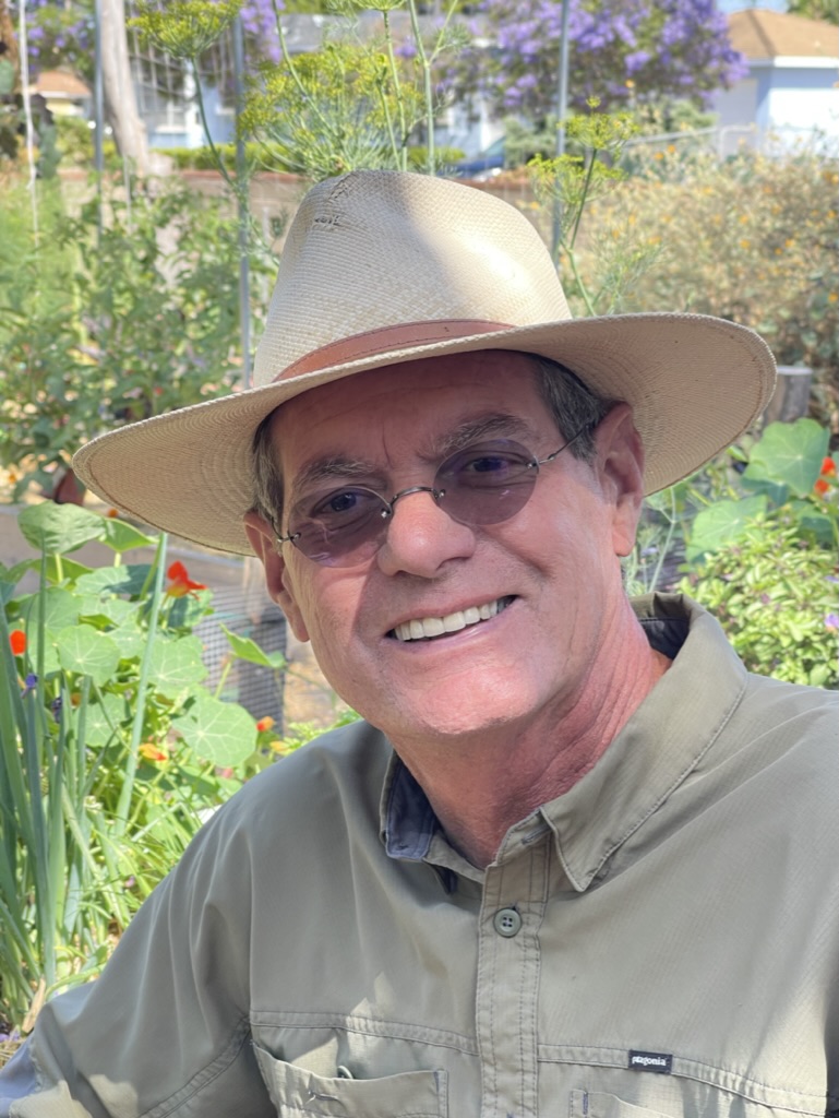 Smiling man with a hat with a garden in the background