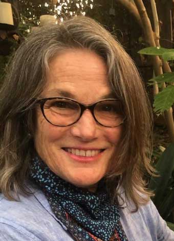 Headshot of a smiling women wearing glasses with bamboo in the background