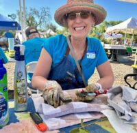 Smiling UC Master Gardener DeLAyne Harmon, seated at a worktable cleaning a pair of garden pruners.