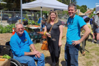 Stephen Cantu sitting in Wheel chair in front of a UC Master Gardener exhibit with a woman and another Master Gardener.